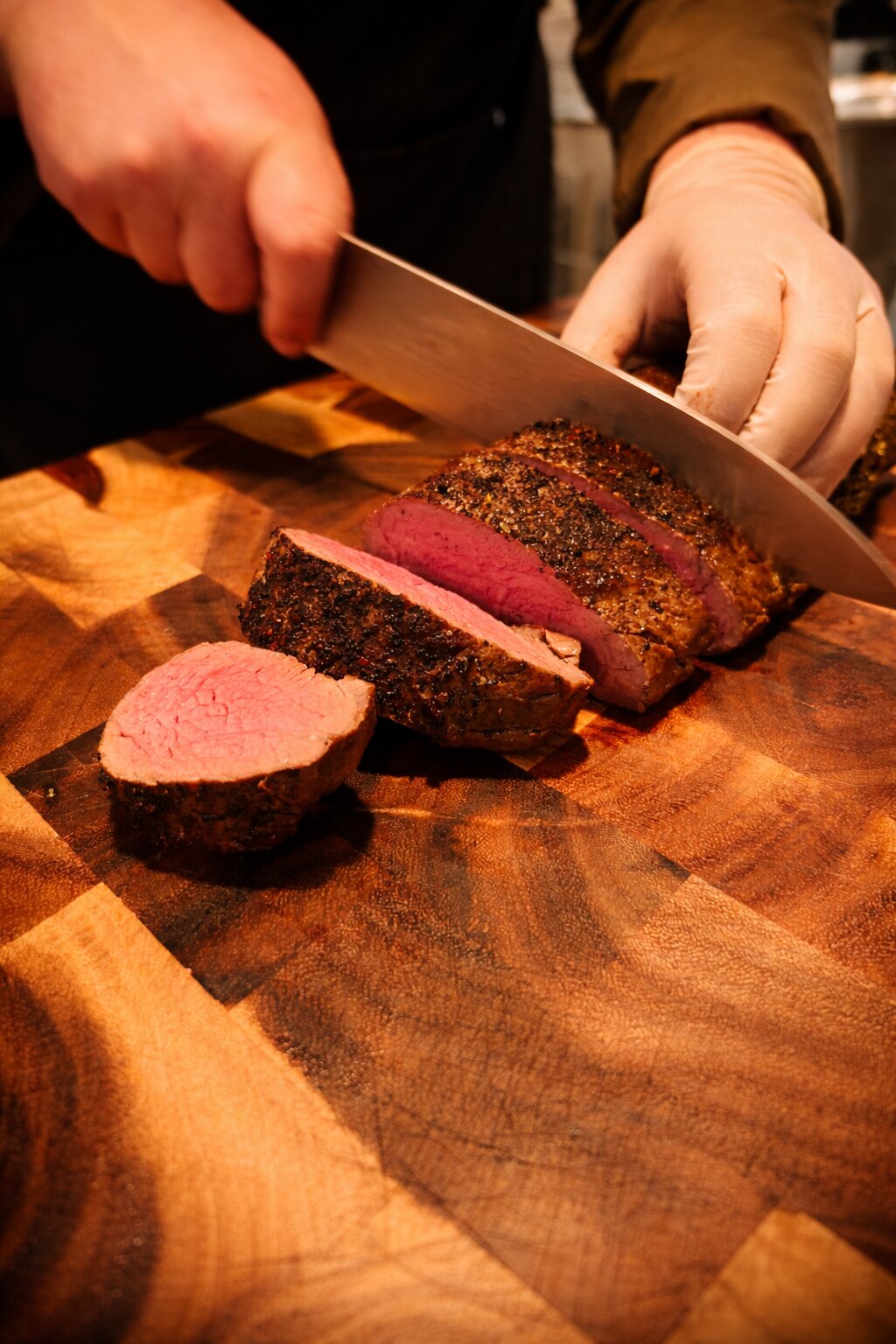 Chef’s Table – Filet am Pass Rosa gebratenes Rinderfilet wird am Pass auf dem Holzbrett tranchiert
