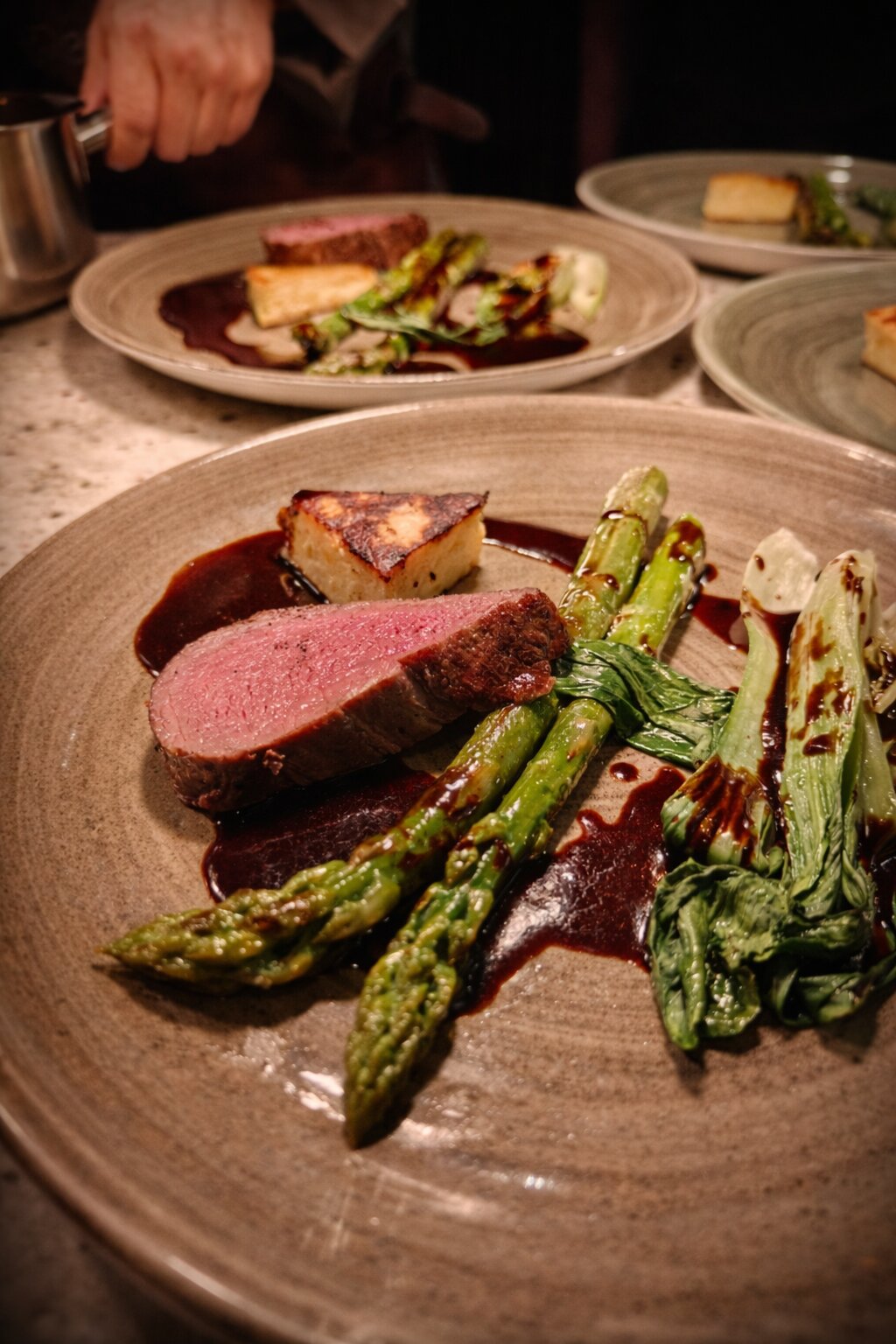 Hauptgang mit rosa gebratenem Rinderfilet, grünem Spargel und Kartoffelgratin