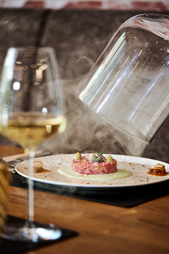 Beef Tartar unter der Rauchglocke, serviert mit einem Glas Weißwein – Das Johann's, Sitzenberg