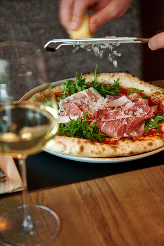 Pizza Dello Chef mit Prosciutto und Rucola, Parmesan wird frisch darübergehobelt – Das Johann's, Sitzenberg